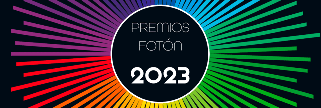 cabecerafoton2023web Texto "Premios fotón 2023" en el centro de los que podría ser un sol del que salen grupos de rayos de distintas longitudes de los colores del arco iris