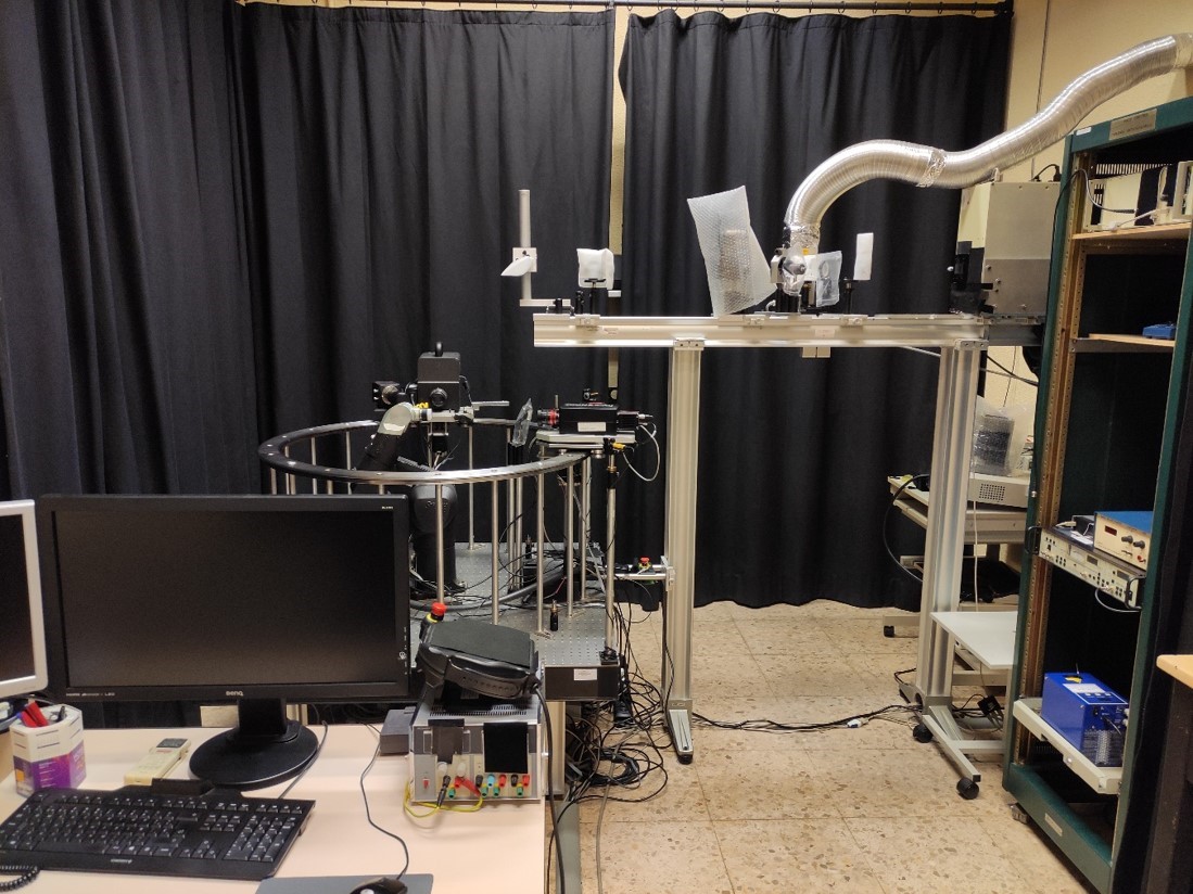 gonioespectrofotometro-gimro2 Equipo científico plateado compuesto por dos patas que sujetan un eje largo que tiene un tubo que baja al centro y diversos equipos de diferentes formas