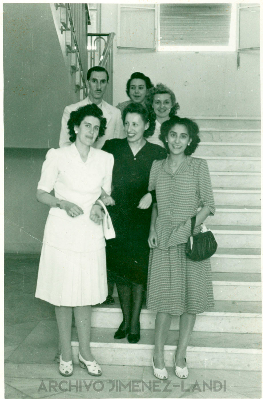 Piedad Vintage black and white photo of 5 young women and a man posing and smiling on the interior stairs of a building